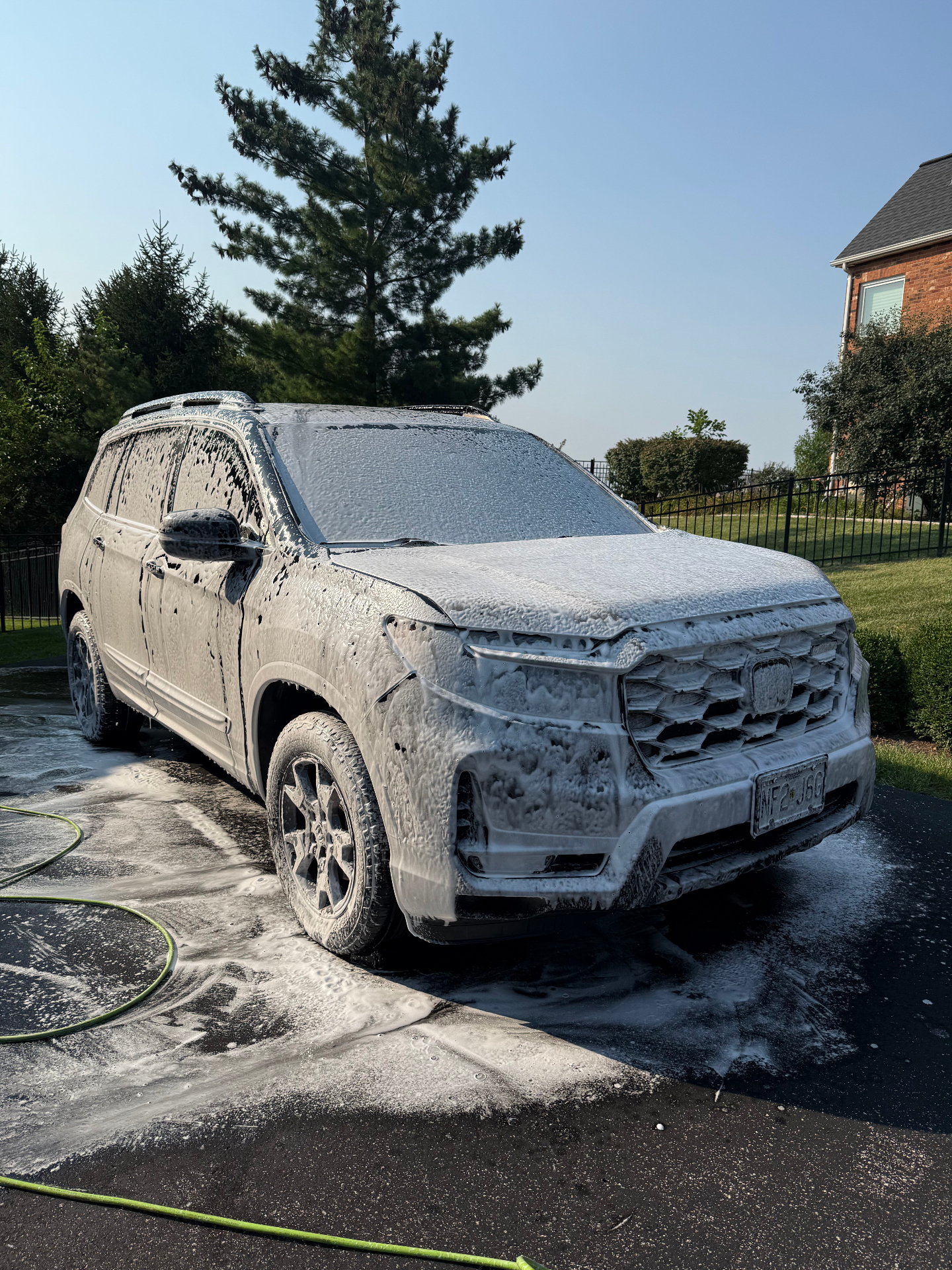 Honda Passport covered in thick foam during an exterior wash in a St. Louis driveway